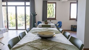Ein Essbereich mit Tisch für vier Personen, Stühlen, einer Pflanze und einem Fenster mit Vorhängen.
