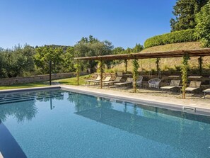 Ein Pool mit Liegestühlen und einer Pergola.
