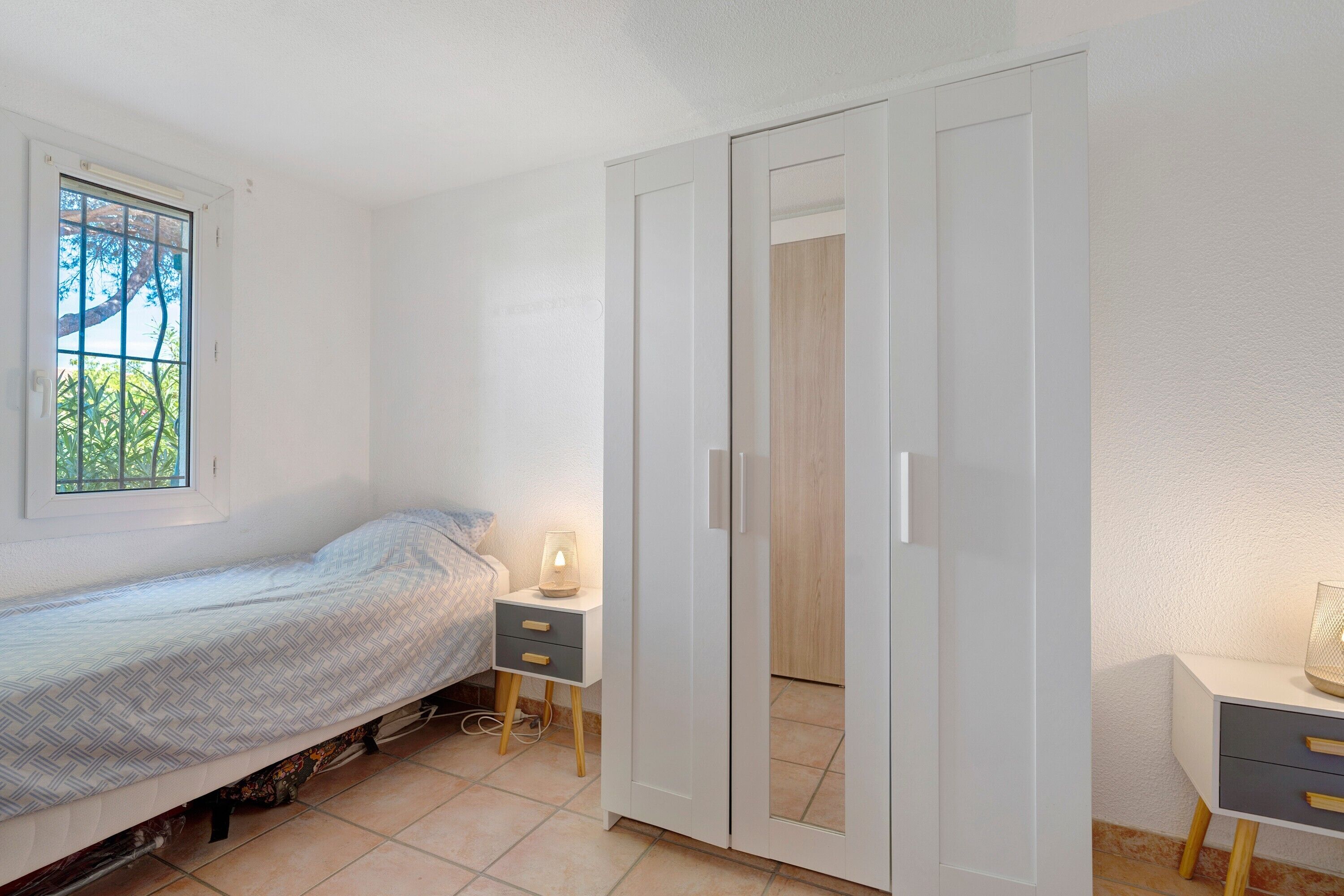Une chambre à coucher avec un lit, une table de chevet, une lampe et une armoire.