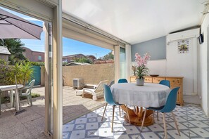A patio with a table and chairs, a potted plant, and a view of the neighborhood. - Villa 80m from Grazel Beach – Wifi, Parking, Sleeps 7 (Gruissan)