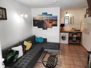 A living room with a sofa, a glass coffee table, and a wall-mounted painting.