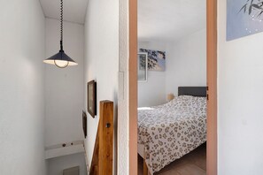 A bedroom with a bed, a hanging lamp, and wall art.