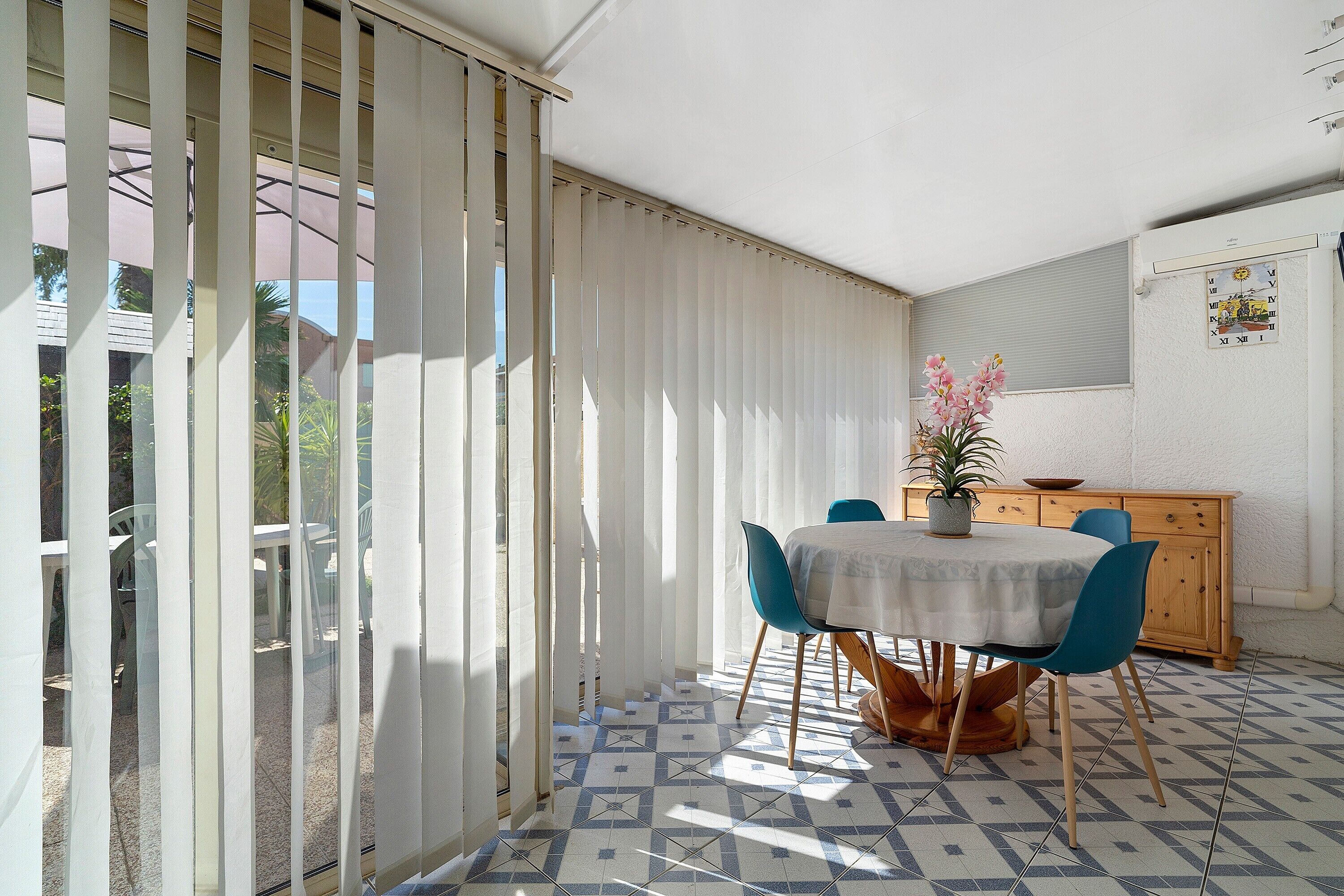 A dining area with a table, chairs, a potted plant, and a wooden cabinet.
