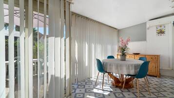 A dining area with a table, chairs, a potted plant, and a wooden cabinet.