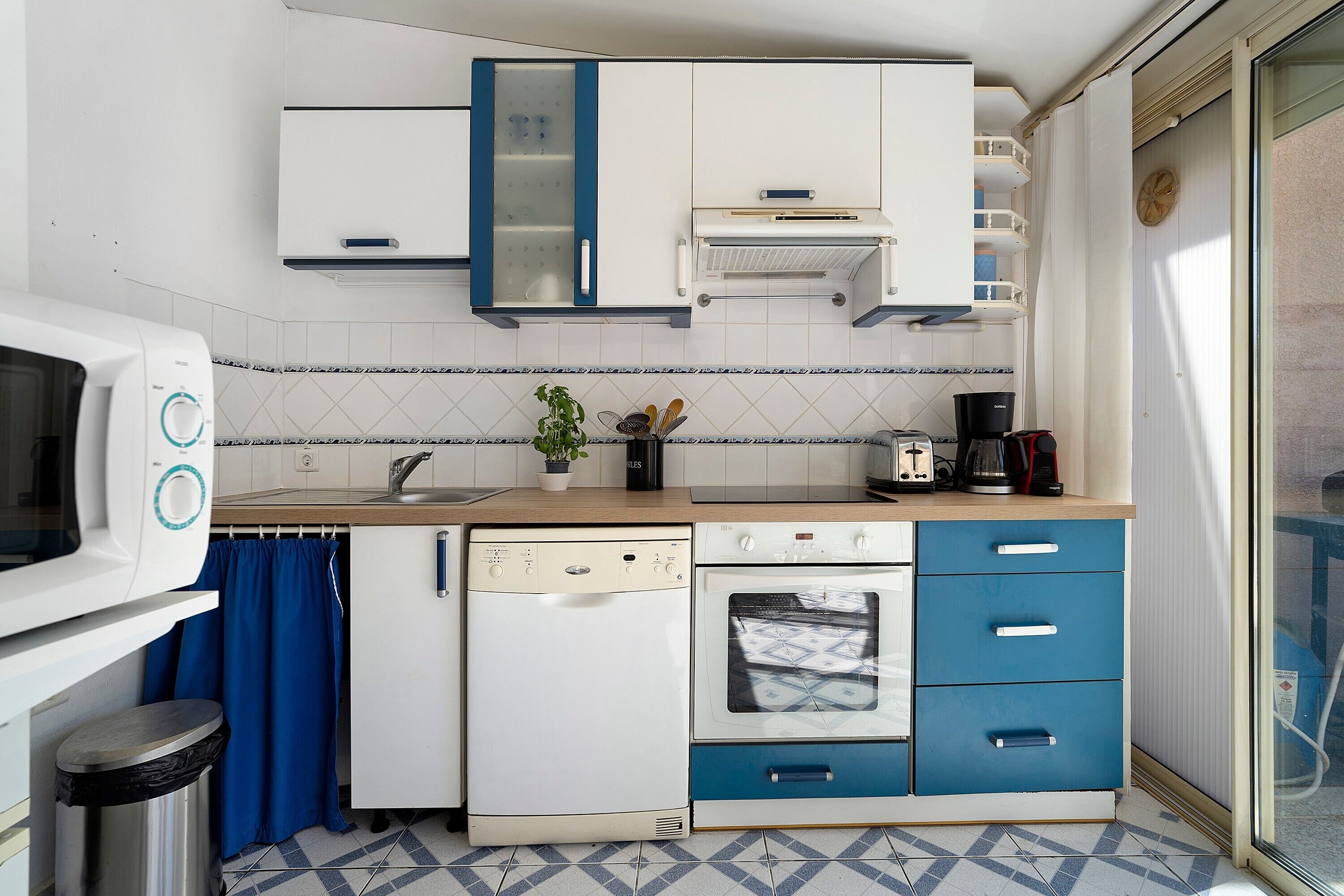 A compact kitchen with a dishwasher, oven, and a coffee maker.