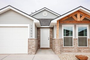 A residential house with a garage, a front door, and two windows. - The Jade - Cozy Lubbock Getaway - Sleeps 6 (Lubbock)