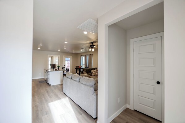 A modern kitchen with a central island, a dining area with a table and chairs, and a living area with a sofa. - The Jade - Cozy Lubbock Getaway - Sleeps 6 (Lubbock)