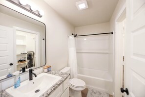 A bathroom with a sink, mirror, and shower. - The Jade - Cozy Lubbock Getaway - Sleeps 6 (Lubbock)