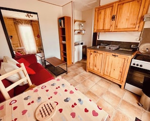 A compact kitchen with wooden cabinets, a stove, and a small dining area with a table and chairs. - Small Provencal cocoon (L'Isle-sur-la-Sorgue)