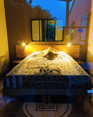 A bedroom with a bed, a nightstand, a mirror, and a window with a view of trees. - Small Provencal cocoon (L'Isle-sur-la-Sorgue)