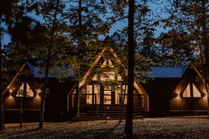 A cabin with a triangular roof, wooden exterior, and a porch with steps leading to the entrance. - Luxury Couples or Family Cabin/Hot Tub/Fire Pit (Broken Bow)