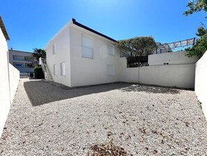A white building with a gravel courtyard, a staircase, and a tree. - Magnificent apartment with sea view (Palavas-les-Flots)