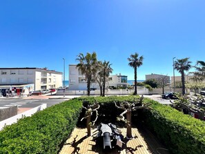 A coastal area with buildings, palm trees, and a paved walkway. - Magnificent apartment with sea view (Palavas-les-Flots)