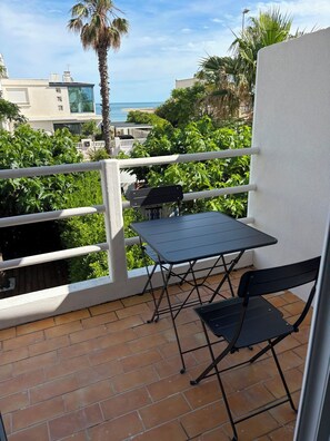 Un balcon avec une table et des chaises, une vue sur l’océan et une végétation luxuriante tout autour.