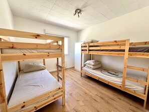 Une pièce avec deux lits superposés en bois, un plafond blanc et une fenêtre.