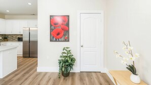 A modern kitchen with white cabinets, a stainless steel refrigerator, and a wooden floor. - Reed Unit B - Home & Private Rooms (Houston)