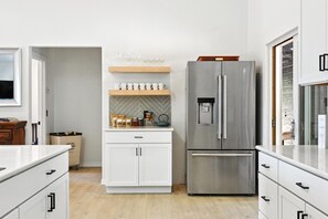 A modern kitchen with white cabinetry, a stainless steel refrigerator, and a herringbone-patterned backsplash. - Seaside Ridge Above the Fog | Hot Tub, Ocean View (Gualala)