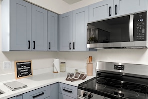 Une cuisine moderne avec des meubles gris, un four à micro-ondes en acier inoxydable et une cuisinière noire.