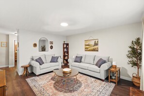 A modern living room with two sofas, a coffee table, a bookshelf, and a large painting on the wall. - Cozy up in The Book Nook 2 - minutes from downtown Chesterton and Indiana Dunes (Chesterton)