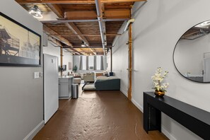 A hallway with exposed wooden beams, a bed, a desk, and a mirror on the wall.