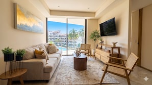 Un salon moderne comprenant un canapé, une table basse et des fauteuils, un téléviseur à écran plat et un balcon avec vue sur la piscine.