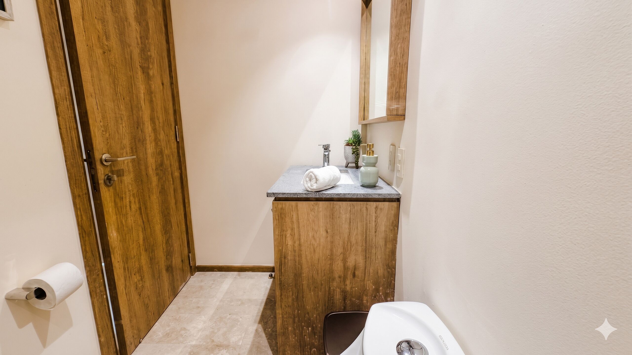 A bathroom with a wooden vanity, a towel, a small potted plant, and a mirror.