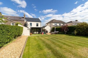 A residential property with a well-maintained lawn, a patio area, and a large house with a garage.
