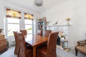 A dining room with a wooden table and leather chairs, a fireplace, and shelves with decorative items.