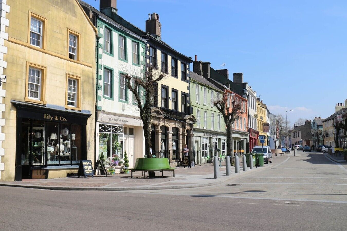 A street with buildings, a bench, and a sign for 'Lily & Co.'