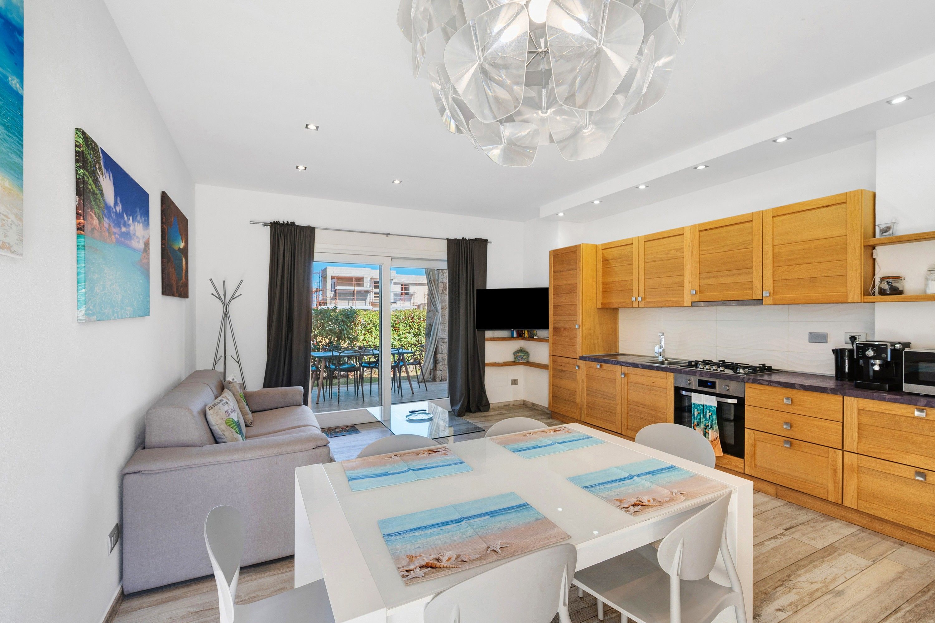 A modern apartment with a dining area, kitchen, and a balcony with a view of buildings and greenery.