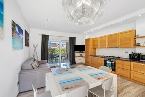 Ein modernes Apartment mit Essbereich, Küche und einem Balkon mit Blick auf Gebäude und Grünflächen.