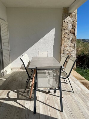 Een terras buiten met een tafel, stoelen, een stenen muur en uitzicht op het landschap.