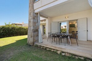 An outdoor patio area with a table and chairs, a stone pillar, and a view of a building in the background. - R House II: Your Paradise Retreat in Budoni (Budoni)