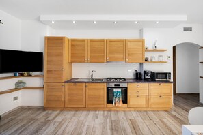 Eine moderne Küche mit Holzausbau, einem Backofen, einer Mikrowelle und einer Kaffeemaschine.