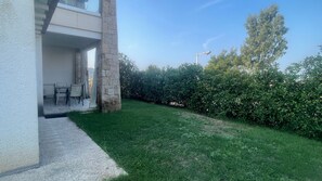 A residential property with a stone pillar, a patio with a table and chairs, and a well-maintained lawn. - R House II: Your Paradise Retreat in Budoni (Budoni)