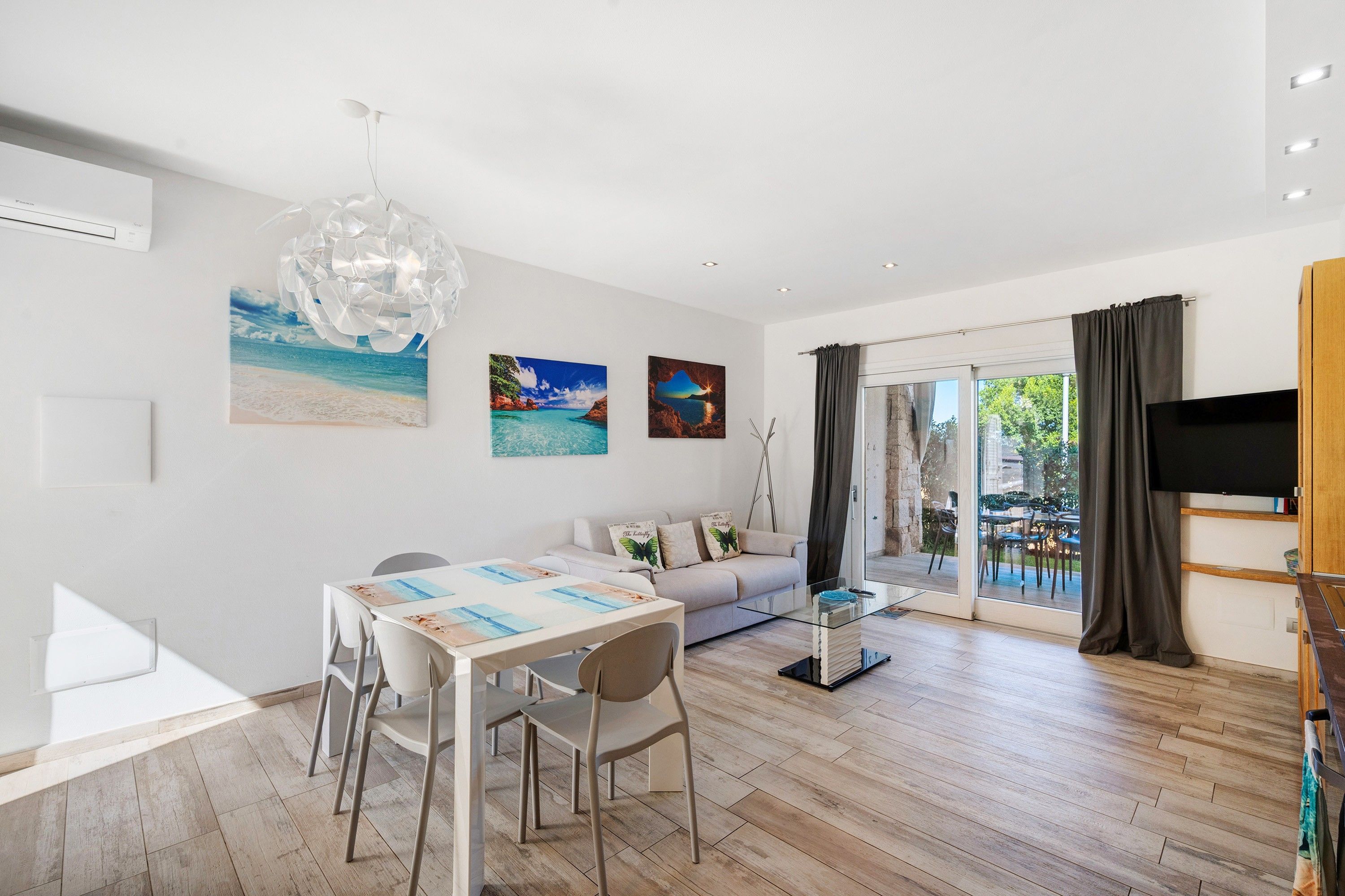 En moderne stue med spiseområde, sofa og fjernsyn.