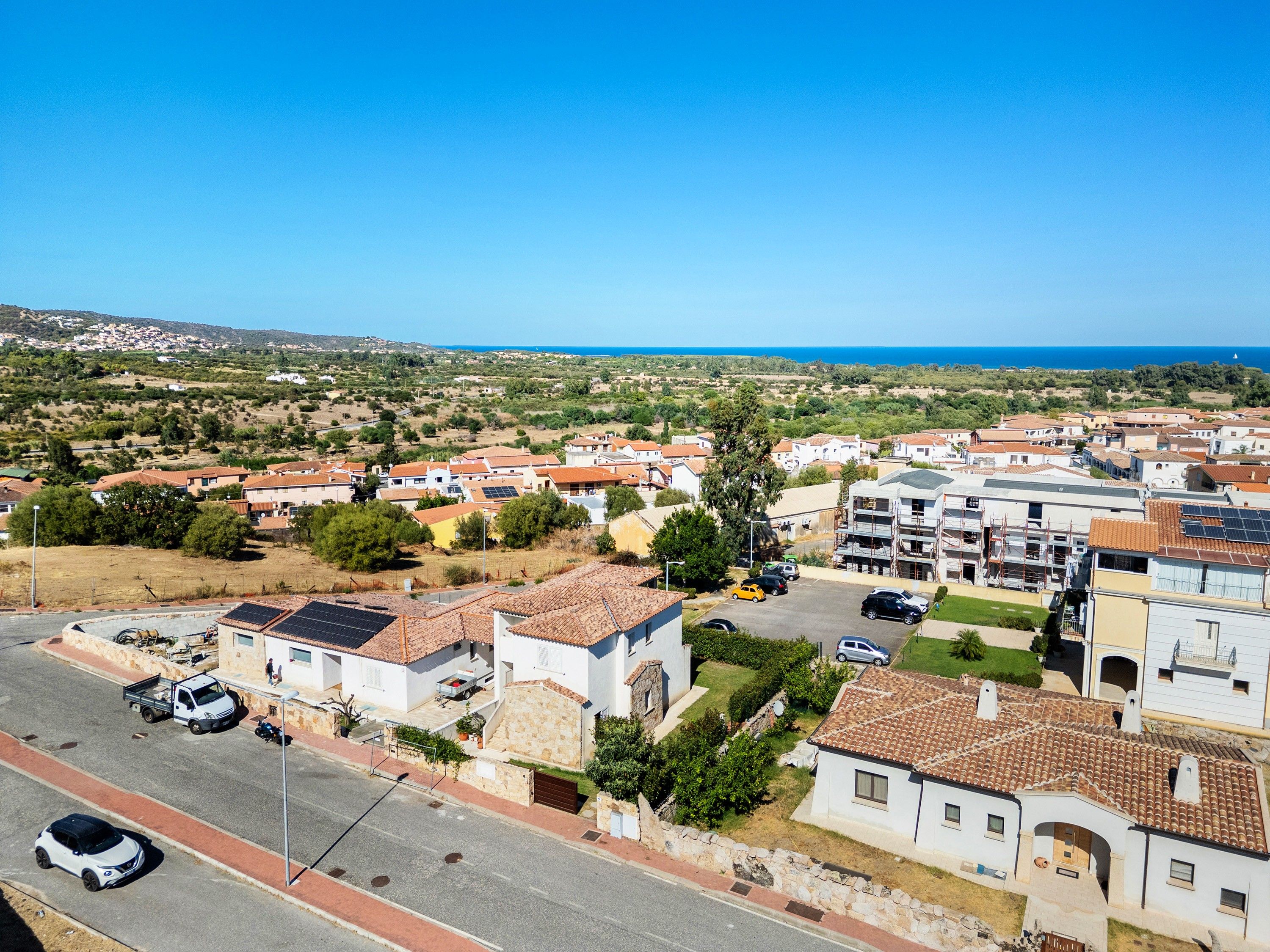 Un quartier résidentiel avec des maisons, une rue et une vue dégagée sur la mer.