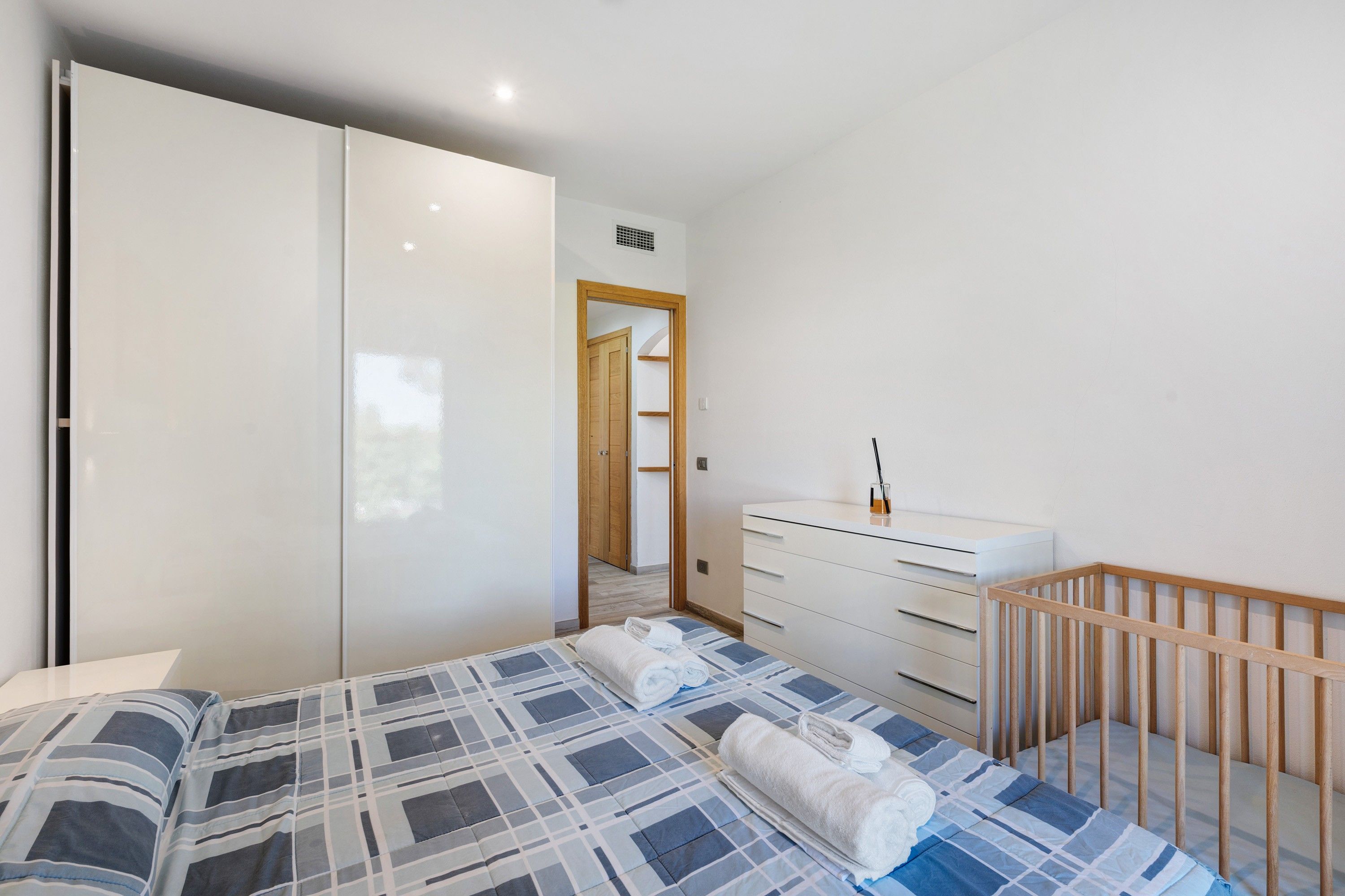 Ein Schlafzimmer mit einem Bett, einer Kommode, einem Kinderbett und einem Kleiderschrank.