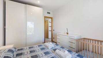 Ein Schlafzimmer mit einem Bett, einer Kommode, einem Kinderbett und einem Kleiderschrank.