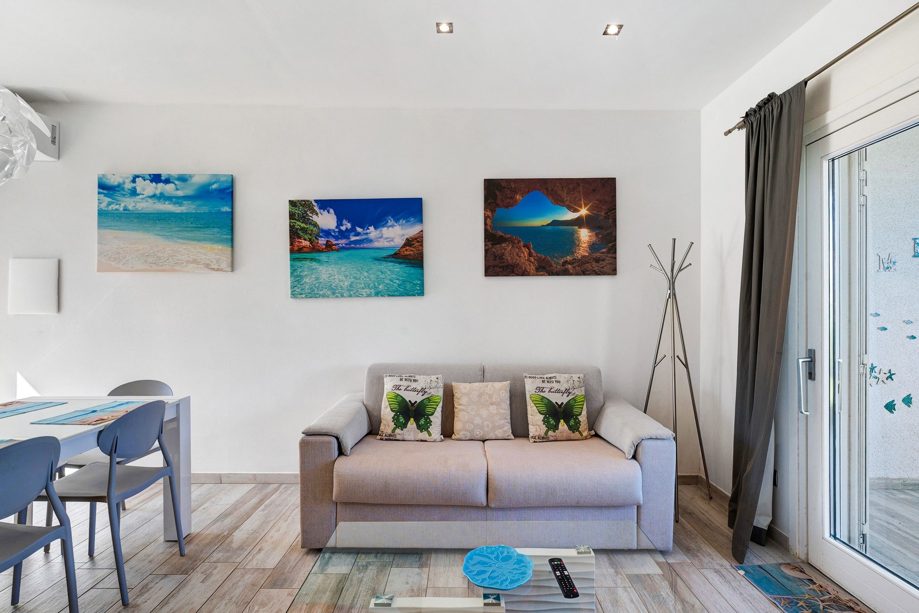 En moderne stue med en sofa, et spisebord med stole og tre billeder hængende på væggen.