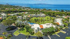 A residential area with multiple buildings, a swimming pool, and a view of the ocean. - Ground Floor Wailea Condo with Private Lanai Near Beaches (Kihei)