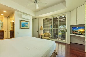 Una camera d'albergo con un letto, una televisione, una sedia e un balcone con vista.