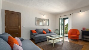 Una sala de estar con un sofá, un sillón, una mesa de centro y una puerta.