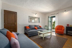 Ein Wohnzimmer mit Sofa, Sessel, Couchtisch und einer Tür.