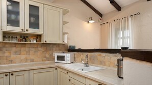 Una cocina equipada con microondas, pileta y alacenas.