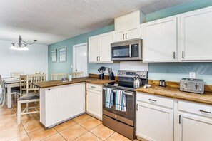 Eine Küche mit weißen Schränken, einer Mikrowelle, einem Backofen, einem Toaster und einem Essbereich mit Stühlen und einem Tisch.