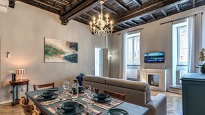 Ein Essbereich mit einem Tisch für vier Personen, einer Kandelaber, einem Gemälde und einem Fernseher an der Wand.