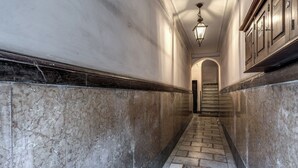 Eine mit Marmor verkleidete Diele mit Treppe, einer Leuchte und Holzschränken.
