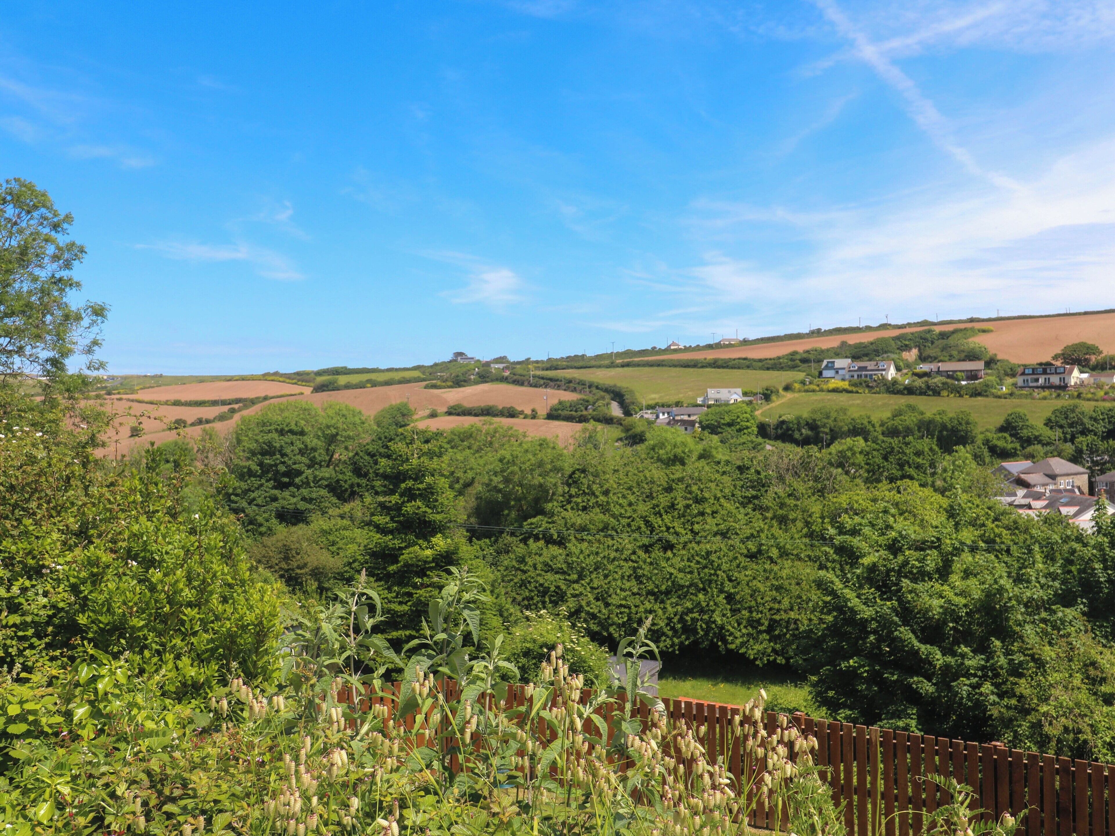 Un paysage rural caractérisé par des collines douces, des maisons dispersées et une végétation luxuriante.