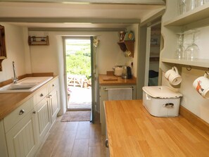 A kitchen with a sink, wooden countertop, and a view to the outside. - Greenways (Perranporth)
